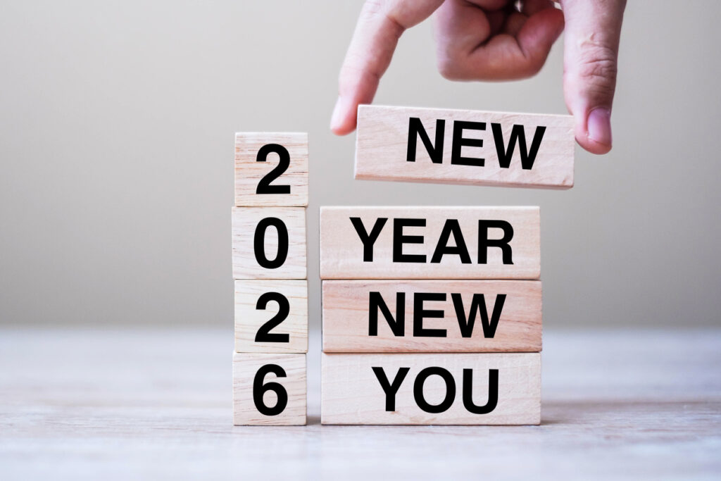 Hand holding wooden block with text 2026 NEW YEAR NEW YOU on table background. Resolution, strategy, goal, business and holiday concepts